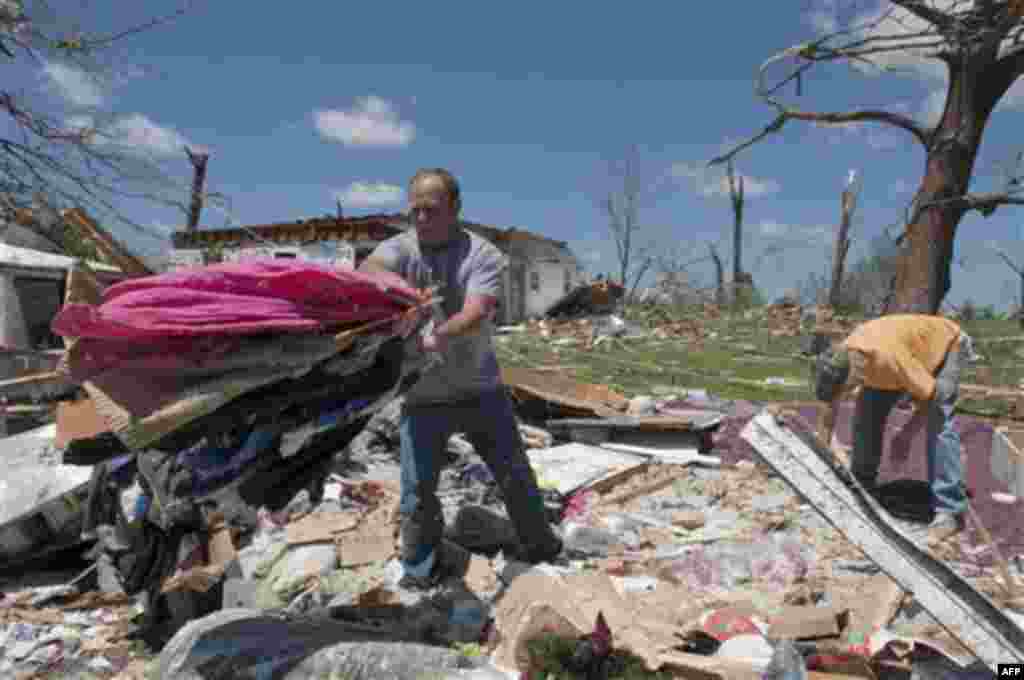 Mark Plunkett, left, with the help of Allen Southerland, right, find some of his wife's clothing in the debris of his home in Phil Campbell, Ala., Thursday, April 28, 2011. They where not home when the storm hit but at a church up the street. (AP Photo/Bo