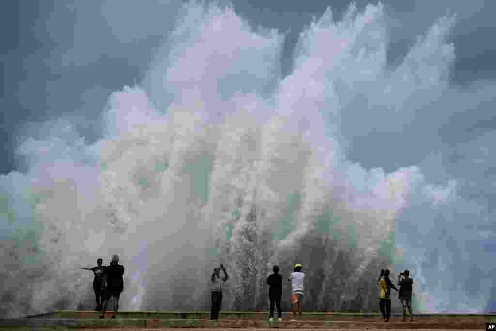 Orang-orang mengambil foto semburan ombak besar yang menghantam tanggul Malecon, akibat Badai Milton di Teluk Meksiko, di ibu kota Havana, Kuba. (AP)&nbsp;