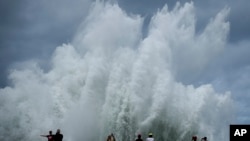 People take photos of the spray from waves crashing against the Malecon seawall, brought by the passing of Hurricane Milton in the Gulf of Mexico, in Havana, Cuba.
