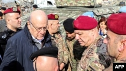 Lebanon's caretaker Prime Minister Najib Mikati (2nd-L) and Lebanese army commander, General Joseph Aoun (2nd-R), visit the southern Lebanese village of Khiam on Dec. 23, 2024, after the withdrawal of Israeli forces from the area. 