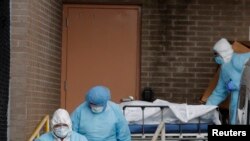 Trabajadores de la salud transportan los cuerpos de las personas fallecidas en el Wyckoff Heights Medical Center durante el brote de COVID-19 en el distrito de Brooklyn de la ciudad de Nueva York, el 2 de abril de 2020.