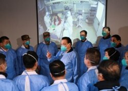 Chinese Premier Li Keqiang wearing a mask and protective suit speaks to medical workers as he visits the Jinyintan hospital where the patients of the new coronavirus are being treated in Wuhan, Hubei province, Jan. 27, 2020.
