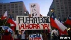A person who is against the proposed new constitution holds signs reading "No means no" and "Boric out now" as they react to results of the referendum on a new Chilean constitution, in Santiago, Chile, Dec. 17, 2023.
