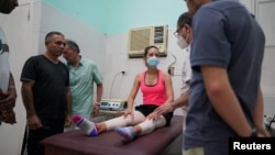 A ballet dancer speaks to Chilean Kinesiologist Mauro Model in a physiotherapy room at a ballet's school in Havana, Cuba, August 18, 2022. (REUTERS/Alexandre Meneghini)