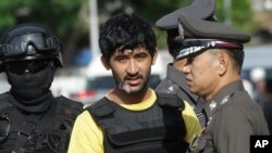 Police officers escort a key suspect in last month's Bangkok bombing, yellow shirt, identified by Thai police as Yusufu Mierili, also as Yusufu Mieraili, traveling on a Chinese passport, but his nationality remains unconfirmed, outside Hua Lamphong railwa