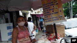 A street vendor wearing a mask amid COVID-19 sells cheese, beans and sweets in Rio de Janeiro, Brazil, Oct. 9, 2020. Many people in Brazil are struggling to cope with less pandemic aid from the government and jumping food prices.