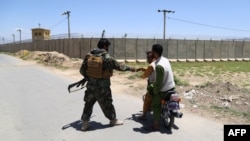 An Afghan National Army (ANA) soldier salutes locals riding on a motorbike outside Bagram Air Base, after all US and NATO troops left, some 70 Km north of Kabul on July 2, 2021. (Photo by Zakeria HASHIMI / AFP)