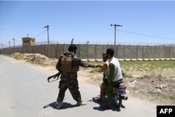 بگرام ایئر پورٹ کے قریب ایک افغان فوجی وہاں سے گزرنے والے موٹرسائیکل سواروں سے پوچھ گچھ کر رہا ہے۔ 2 جولائی 2021