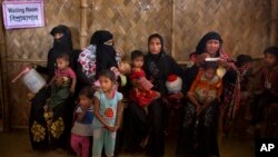 Rohingya Muslim refugee women with their children wait at a nutrition center to collect the diet for their children at Balukhali refugee camp 50 kilometres (32 miles) from, Cox's Bazar, Bangladesh, Jan. 23, 2018. 