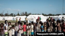 Des enfants font la queue pour recevoir une distribution de nourriture d'un supermarché local dans un centre d'évacuation à Dondo, à environ 35 km au nord de Beira, au Mozambique, le 27 mars 2019. (Photo de Yasuyoshi CHIBA / AFP) 