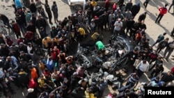 Palestinos inspeccionan un automóvil golpeado por un ataque israelí en Rafah, Franja de Gaza, el 10 de febrero de 2024.