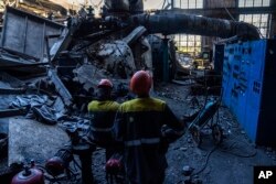 Para pekerja berdiri di antara puing-puing pembangkit listrik tenaga panas milik DTEK yang rusak pasca serangan Rusia di Ukraina, Kamis, 2 Mei 2024. (Foto: AP)