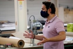 In this June 12, 2020 photo, director Thomas Delise gestures in Chanteclair Hosiery, a French knitwear clothing manufacturer in Saint Pouange, east of Paris, that began making masks to combat the spread of the coronavirus.