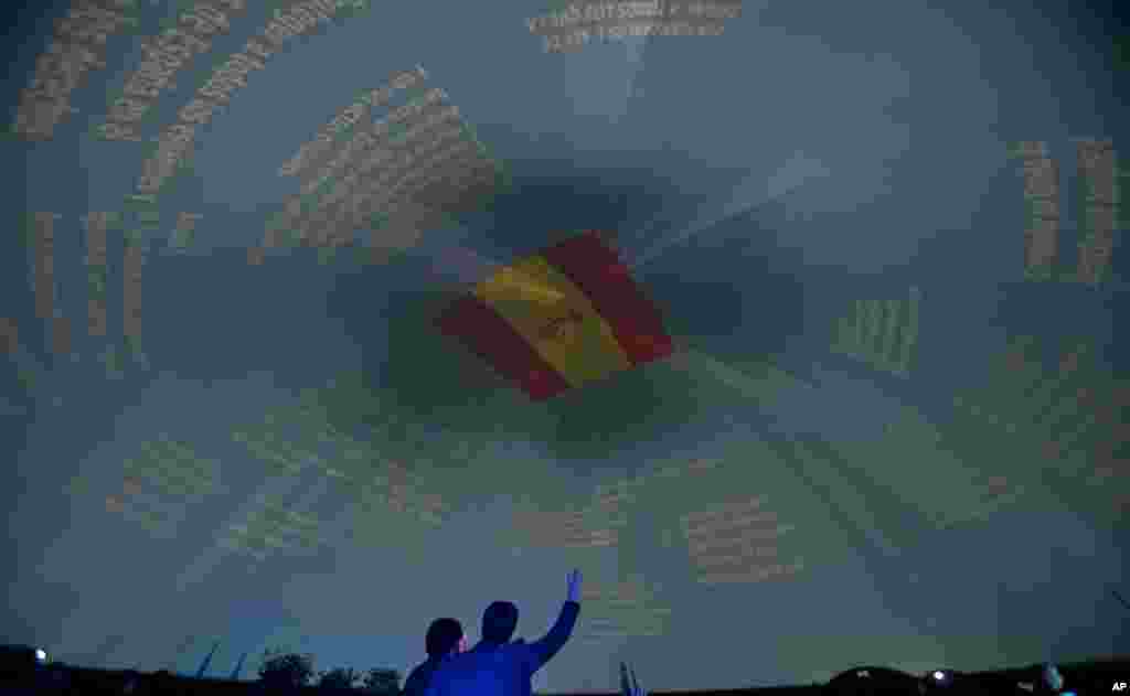 A man raises his hand beneath an image of a Spanish flag in Madrid, Spain. Spain will celebrate the XXXV anniversary of the Spanish Constitution Dec. 6, 2013.