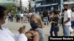 Un trabajador de la salud administra una vacuna a una mujer en Río de Janeiro, Brasil en abril de 2021.