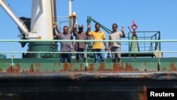 FILE - Crew members wave aboard oil tanker Aris-13, which was released by pirates, as it sails to dock on the shores of the Gulf of Aden, northern Somalia's semi-autonomous region of Puntland, March 19, 2017.