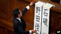 A staff member at parliament puts up two names, Shigeru Ishiba and Yoshihiko Noda for a runoff vote for a new prime minister at a special parliamentary session of the lower house, Nov. 11, 2024, in Tokyo.