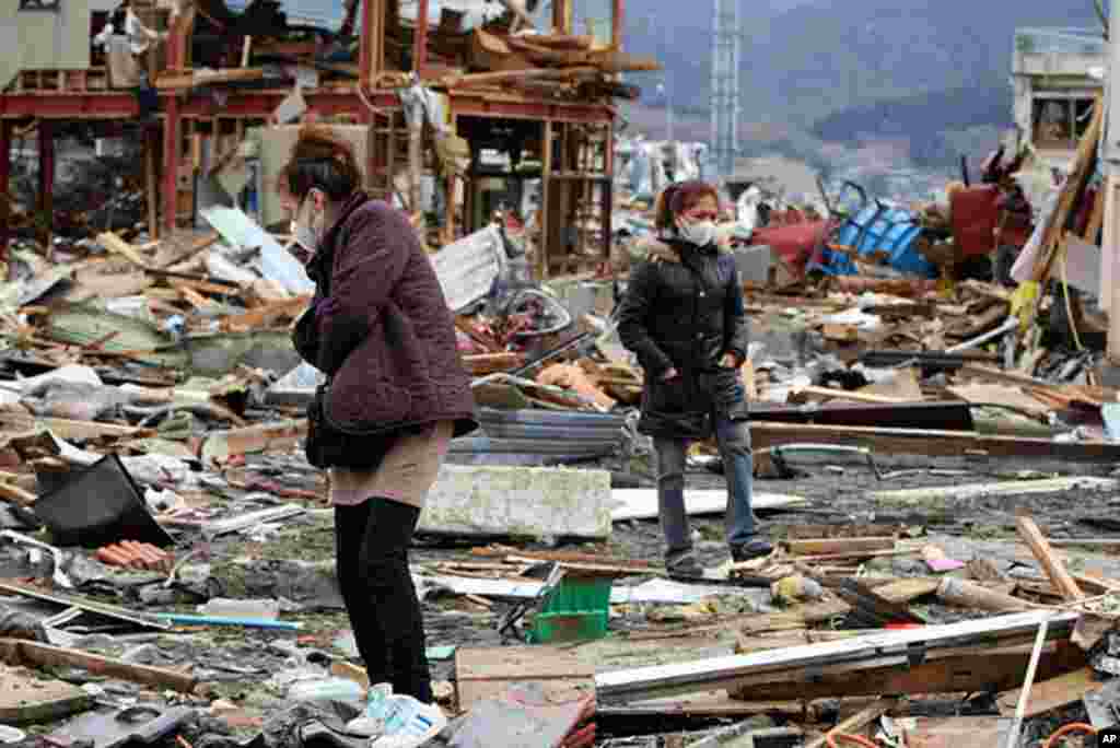 A restaurant owner (L) and her employee walk on the debris where their restaurant stood before the tsunami devastated the area, at Ofunato city in Iwate prefecture on March 22, 2011, (AFP) 