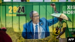 A supporter of the ruling Kulmiye party walks past a banner showcasing the incumbent president of Somaliland and presidential candidate Muse Bihi Abdi following Kulmiye's final campaign rally in Hargeisa on Nov. 9, 2024.