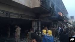 Pekerja darurat berkumpul di lokasi ledakan bom mobil di utara kota Irbil, Irak, Jumat, 17 April 2015. Sebuah bom mobil meledak di luar Konsulat AS di kota Irbil, Irak utara. (Foto: AP)