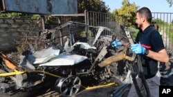 FILE - A civil defense worker carries parts of a destroyed car in the southern town of Bazouriyeh, Lebanon, January 20, 2024. An Israeli drone strike on the car near the Lebanese southern port city of Tyre killed two people, the state-run National News Agency reported.