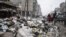A family crosses a street piled with garbage in Aleppo, Syria, January 5, 2013.