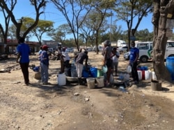 Residents queue for water, May 16, 2020, at a borehole sunk by the U.N. as part of efforts to contain waterborne disease in Harare. Some residents say hygiene problems may make it hard to fight COVID-19. (Columbus Mavhunga/VOA)