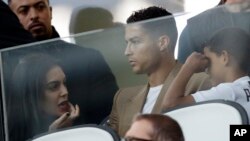 FILE - Soccer superstar Cristiano Ronaldo, center, flanked by his girlfriend Georgina, left, and his son Cristiano Jr, sits in the stands during a Champions League game, at Allianz stadium in Turin, Italy, Oct. 2, 2018.