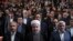 In this photo released by official website of the office of the Iranian Presidency, President Hassan Rouhani, center, Science Minister Mohammad Farhadi, right, and head of the President's office Mohammad Nahavandian, left, listen to the national anthem at the start of a ceremony marking Student Day at Tehran University in Tehran, Iran, Tuesday, Dec. 6, 2016.