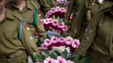 Israeli female soldiers hold wreaths next to the wall of names of fallen soldiers at the Armored Corps memorial, before a ceremony marking the annual Memorial Day for soldiers and civilians killed in more than a century of conflict between Jews and Arabs, in Latrun near Jerusalem.