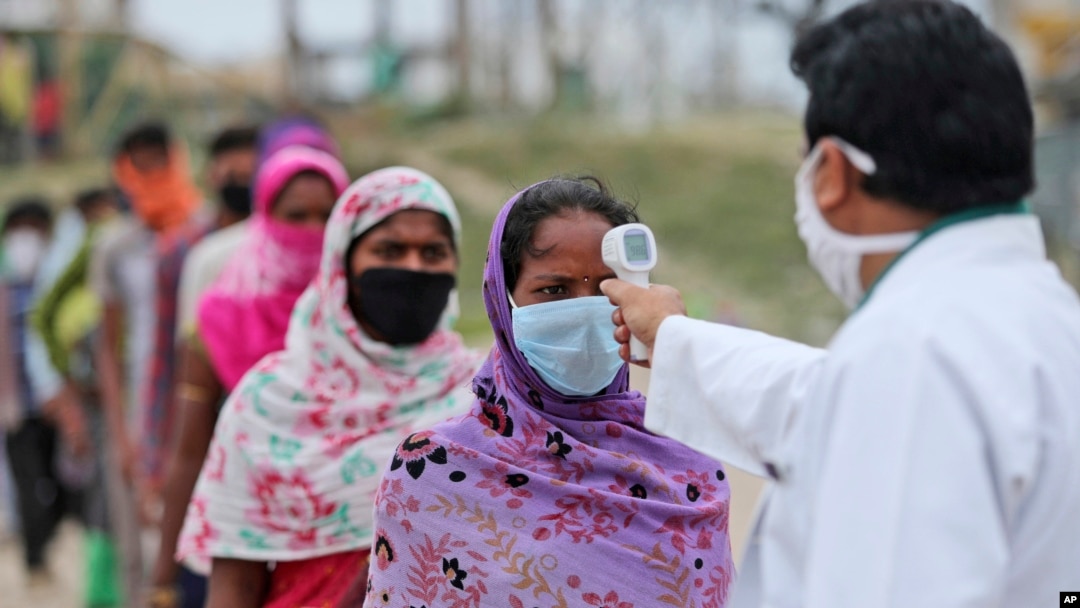 A migrant worker gets her temperature checked before being allowed to board a train tomorrow to head to her home state, in Jammu, India, June.11, 2020. 