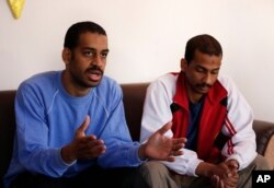 FILE - Alexanda Amon Kotey, left, and El Shafee Elsheikh, allegedly among four British jihadis who made up a brutal Islamic State cell dubbed "the Beatles," speak during an interview with The Associated Press in Kobani, Syria, March 30, 2019.