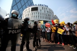 Anti-coup protesters face a row of riot police outside the Hledan Center in Yangon, Myanmar, Feb. 19, 2021.