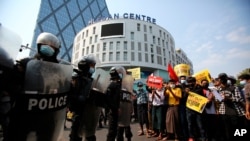 Anti-coup protesters face a row of riot police outside the Hledan Centre in Yangon, Myanmar Friday, Feb. 19, 2021. The daily protests campaigning for civil disobedience in Myanmar are increasingly focusing on businesses and government institutions…