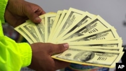 FILE - A police officer shows seized counterfeit dollars to the press in Cali, Colombia, Oct. 9, 2012. 