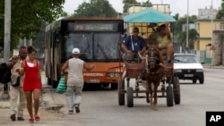 Residentes de La Habana, Cuba, usan un coche tirado por caballos y un autobús el 12 de septiembre de 2019.