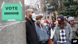 FILE - Voters masked against coronavirus line up at Riverside High School for Wisconsin's primary election, April 7, 2020, in Milwaukee. 