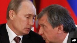 FILE- Russian President Vladimir Putin (L) and CEO of state-controlled Russian oil company Rosneft Igor Sechin speak during a signing ceremony of cooperation agreements with Venezuela, in the Kremlin in Moscow, July 2, 2013.