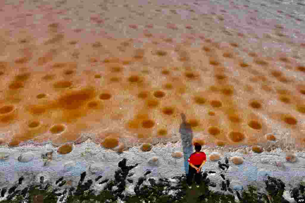 An aerial view shows a man looking at pink colored salt fields, caused by no rain, in Tainan.