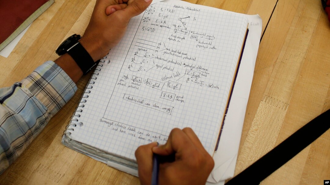 FILE - A student writes notes in the Advanced Placement Physics class at Woodrow Wilson High School in Washington, D.C., February 2014.