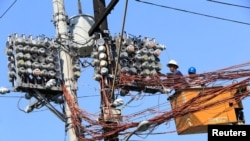 FILE - Filipino lineworkers repair power meters atop electricity post at the main street of Quiapo city, metro Manila, Philippines, Aug. 11, 2017. 