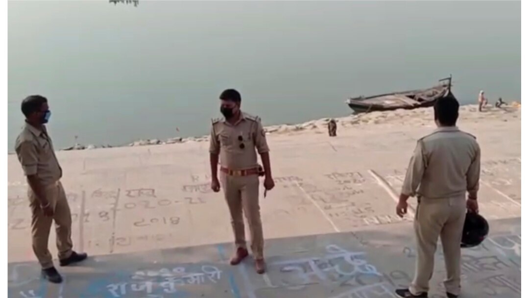 This frame grab from video provided by KK Productions shows police officials standing on the bank of a river where several bodies were found floating, in Ghazipur district, Uttar Pradesh state, India, May 11, 2021.