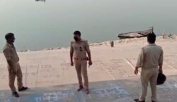 This frame grab from video provided by KK Productions shows police officials standing on the bank of a river where several bodies were found floating, in Ghazipur district, Uttar Pradesh state, India, May 11, 2021.