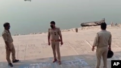 This frame grab from video provided by KK Productions shows police officials standing on the bank of a river where several bodies were found floating, in Ghazipur district, Uttar Pradesh state, India, May 11, 2021. 