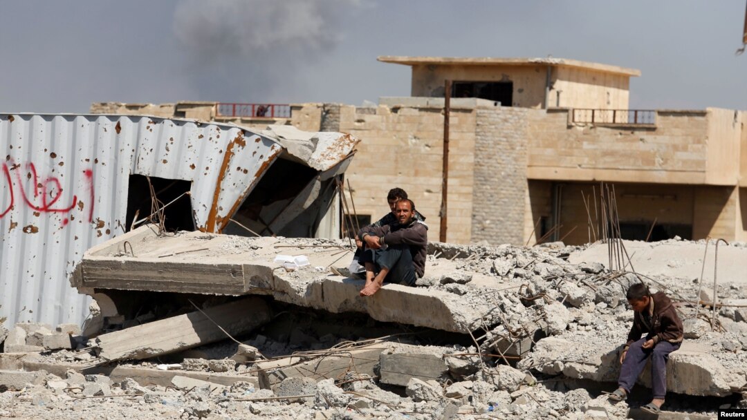 Smoke rises while displaced Iraqis wait to get food supplies as Iraqi forces battle with Islamic State militants, in western Mosul, Iraq, March 27, 2017. 