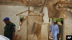 People inspect a damaged mosque following a suicide bomb explosion led by two women in Maiduguri, Nigeria, March 16, 2016. 