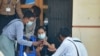 FILE - People check their mobile phones outside an internet shop in Naypyidaw, March 16, 2021, as Myanmar authorities ordered telecommunication companies to restrict their services.