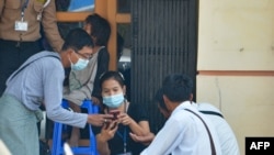 FILE - People check their mobile phones outside an internet shop in Naypyidaw, March 16, 2021, as Myanmar authorities ordered telecommunication companies to restrict their services.