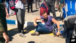 In this frame from video provided by Anapa Today, opposition leader Alexei Navally, center, tries to get up after being attacked at the Anapa airport, southern Russia, May 17, 2016. 