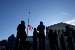 A U.S. flag is seen at half mast as people gather in front of the U.S. Supreme Court following the death of U.S. Supreme Court Justice Ruth Bader Ginsburg, in Washington, Sept. 19, 2020.